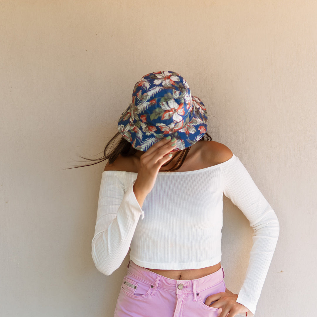 Person wearing a floral headscarf and white long-sleeve top against a plain background