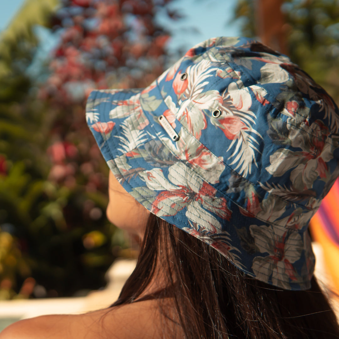 Person wearing a floral bucket hat with a blurred natural background